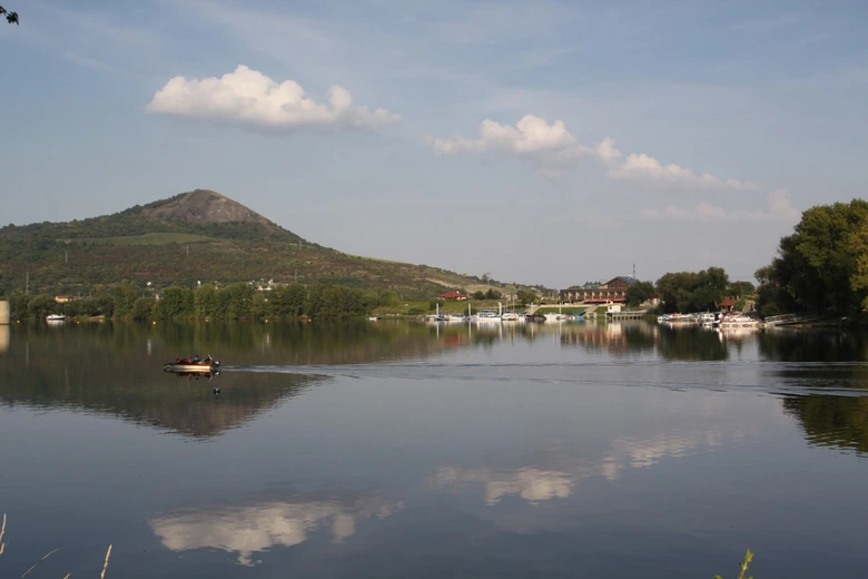 Pohled na klidné Žernosecké jezero s lodí v dálce.