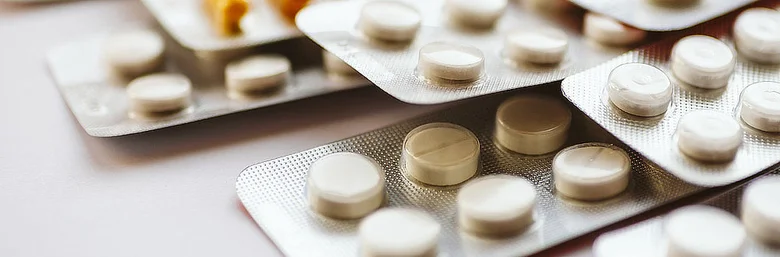 Blistry s bílými antibiotiky na světlém povrchu.
