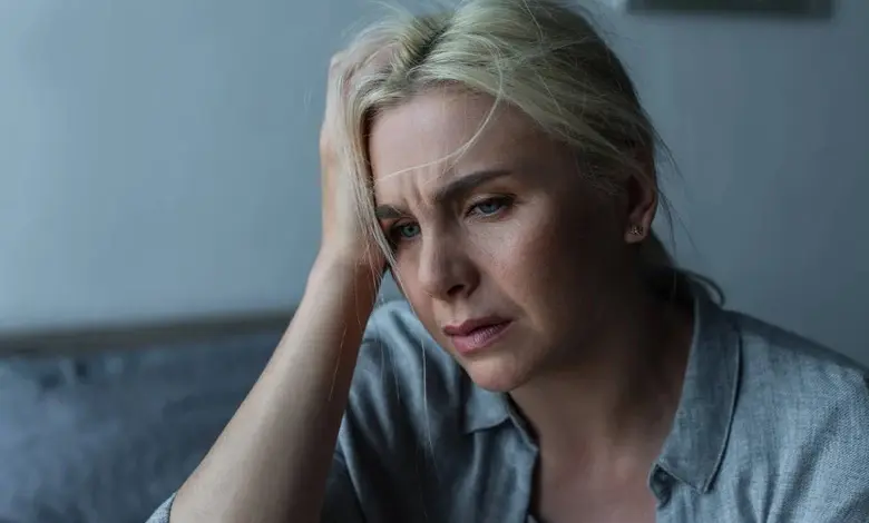 Stresovaná žena s rukou v hlavě ukazuje psychický tlak.