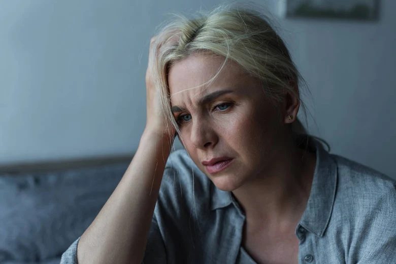 Stresovaná žena s rukou v hlavě ukazuje psychický tlak.