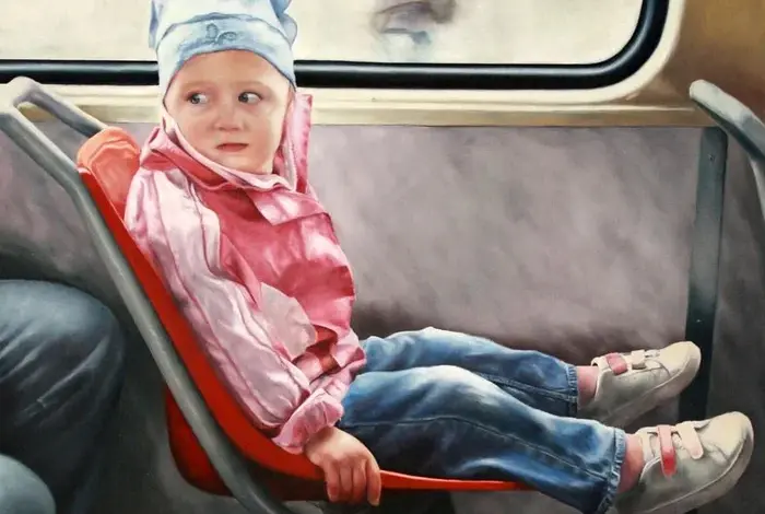 Dětský chlapec sedí sám v autobuse na oranžovém sedačce.