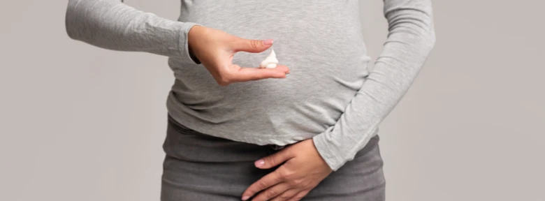Těhotná žena drží v ruce malé množství vaginálního krému.