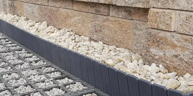 Detail základu kamenné opěrné zdi s odvodňovacím štěrchem a plastovými lištami.