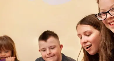 Skupina lidí se usmívá při společné činnosti v interiéru.