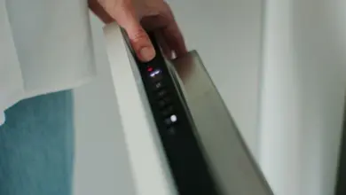 Ruka tlačí na ovládací panel myčky nádobí.