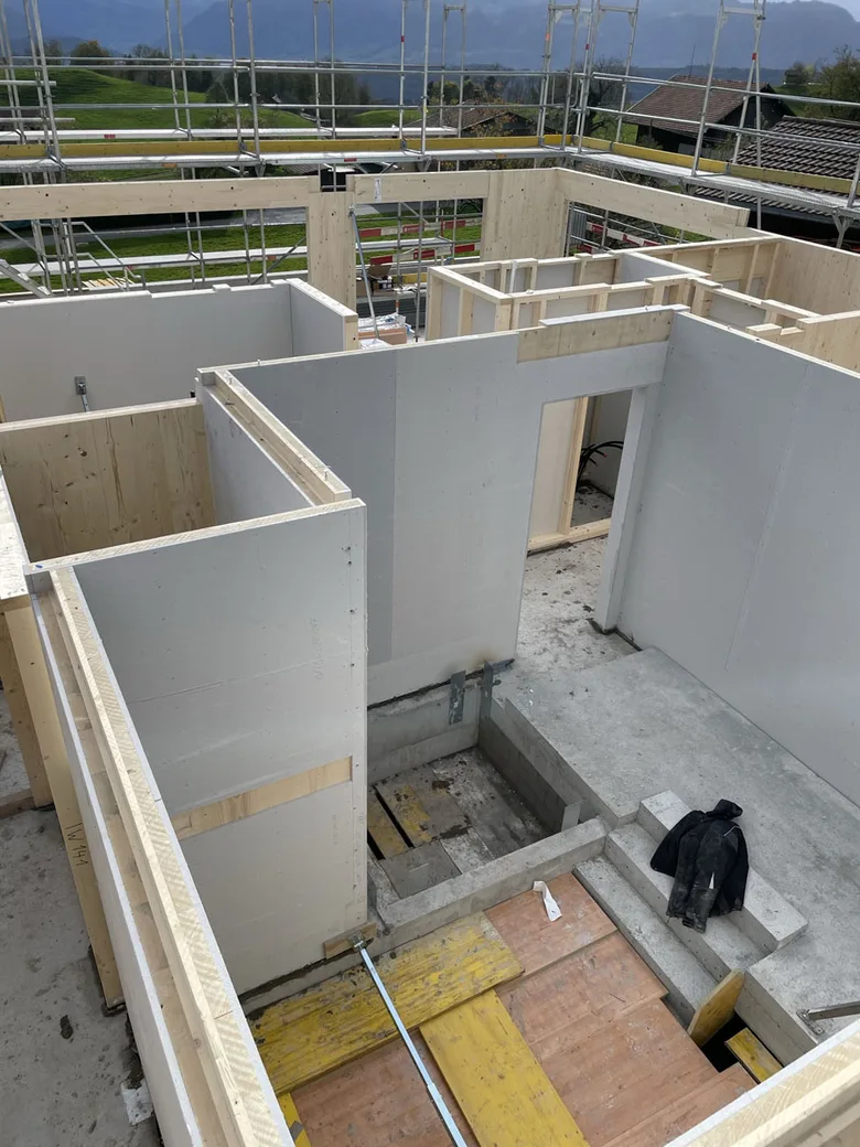 Vnitřní pohled na dům ve výstavbě s instalací CLT panelů mezi dřevěným rámem.