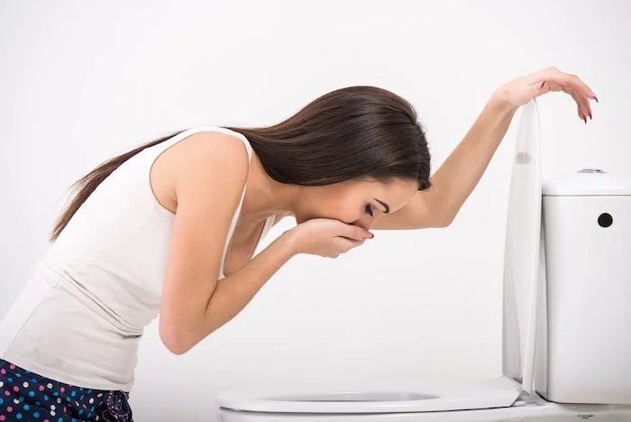 Žena se zvrací do WC před menstruací