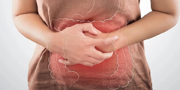 Žena drží břicho s přehledem trávicí soustavy.
