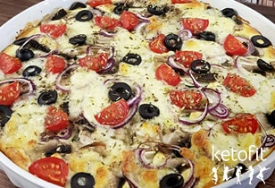 Pizzy s rajčaty, olivami a cibulí na bílém talíři.
