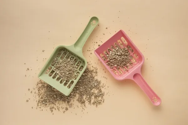 Dvě plastové lopatky na psí zeminu plné granulované podestýlky.